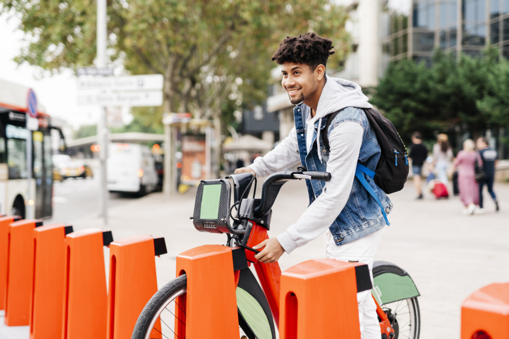 young man using smart phone to pick up a bike on the street.